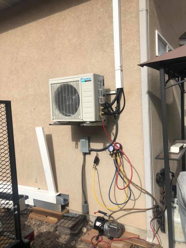 An Outdoor Ductless Mini Split AC unit installation with exposed wires and tools on a residential wall in Provo, UT.