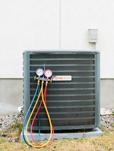 Air conditioning unit with gauges attached, featuring red, blue, and yellow hoses connected to it, likely during an AC installation in Park City, UT.