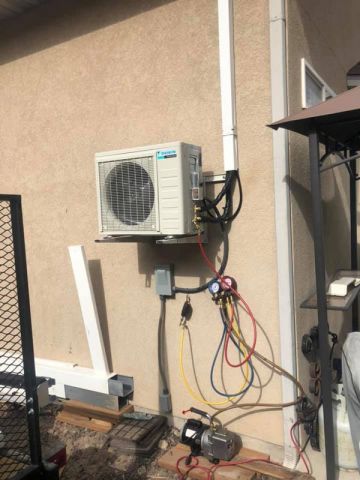 An Outdoor Ductless Mini Split AC unit installation with exposed wires and tools on a residential wall in Midway, UT.