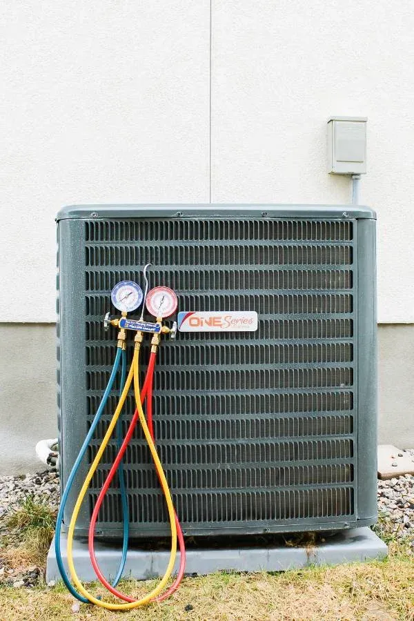 Air conditioning unit with gauges attached, featuring red, blue, and yellow hoses connected to it, likely during an AC Maintenance in Lindon, UT.